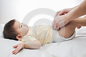 A small cute little baby girl was lying down, her diaper was being changed by her dad