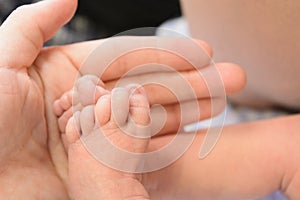 Small cute newborn baby`s feet with man`s hand photo