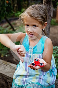 Small cute rural girl doesn`t really like fidget spinner.