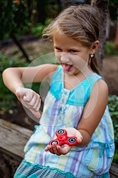 Small cute rural girl doesn`t really like fidget spinner.