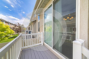 Small deck of a house with sliding glass door and white wood railings