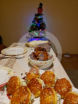 Small decorated with garland and toys Christmas tree with presents under it behind new year table