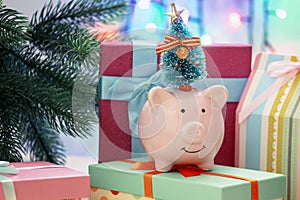 A small decorative pig with a Christmas tree on his head. In the background, gifts and garland.