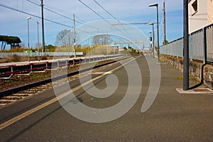 A small deserted local station during the day. sidewalk for waiting passengers waiting for trains for their journeys, between