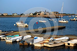 Small dinghies line a pier in a calm harbor