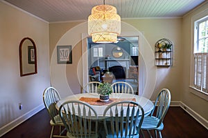 A small dining room with a statement rattan lighting ficture and a painted blue dining room table