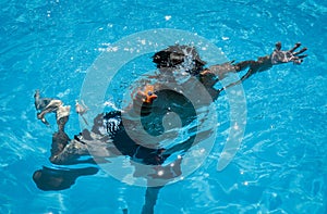 A small diver with a spray gun in the pool under water