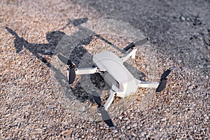 Small drone and a shadow from him standing at the receiving station to prepare for flying away