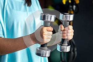 Small dumbbells in the hands of a woman in the gym, close up.