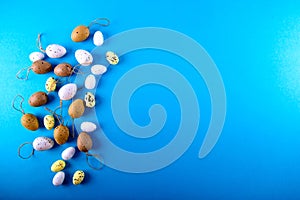 Small easter eggs different size on blue background with copy space.