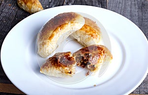 Small empanadas with meat on a white plate.