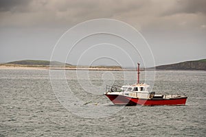 Small empty red color fishing boat in the ocean. Food industry. Nobody. Outdoor sport and activity concept