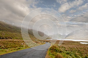 Small empty road leads into mountains. Low cloudy sky, Connemara, Ireland. Nobody. Travel concept