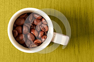 Small espresso cup with the coffee grain on the yellow wooden cafe table