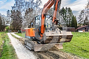 A small excavator levels the dirt road