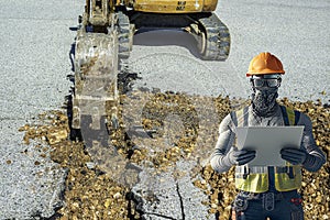 Small excavator with narrow bucket in action for the construction of a channel on a building site