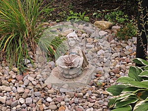 Small fairy like sculpture, rests in the garden