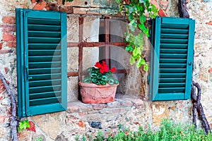 Small fairy tale style window with open green shutters in Monteriggioni, Italian town