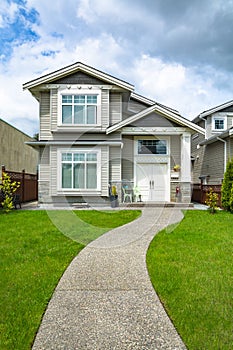 Small family house with curved concrete pathway over green lawn of front yard