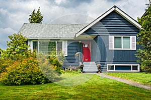 Small family house with green lawn and decorative flowers at the door