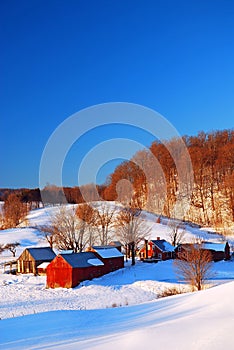 A small farm sits peacefully under a blanket of snow