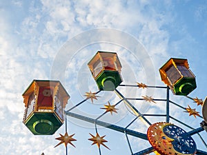 A small Ferris wheel in the park. A bright attraction for children. Entertainment in the park. Colorful booths. High above the