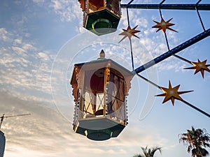 A small Ferris wheel in the park. A bright attraction for children. Entertainment in the park. Colorful booths. High above the