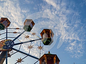 A small Ferris wheel in the park. A bright attraction for children. Entertainment in the park. Colorful booths. High above the