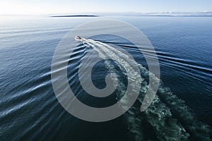 Small ferry boat in blue ocean on the way to Aran island, Ireland. Wake behind cruise ship. Warm sunny day with clear blue sky.