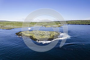 Small ferry boat leaving Doolin harbor on the way to Aran islands, Ireland. Travel and tourism industry. Warm sunny day with blue