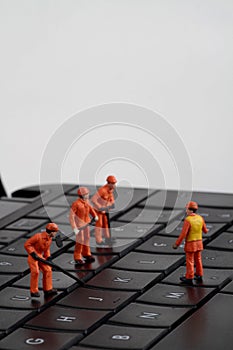 Small figurines of workers repairing computer keyboard