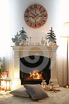 Small fir trees and candles on mantelpiece indoors. Christmas interior design