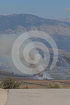 Small fire in valley fire view from hill above Saranda city in Albania