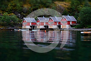 Small fish boat houses at Flam, Norway. Tilt shift effect. Classic red rorbu cabins near the river bank. Fisherman house