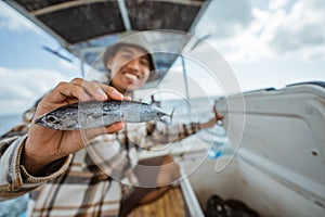 small fish held by an angler while fishing at sea