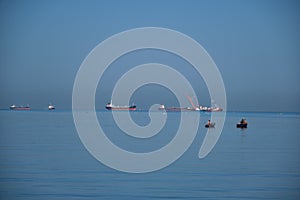 Small Fisherman Boat in the Sea. A small fisherman boat floating on the sea near the seashore with Cargo ship background