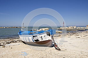 Small fishing blue burnt boat on the seashore