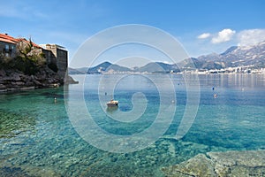 Small fishing boat on the Adriatic sea near Sveti Stefan Island, Montenegro. Turquiose water, islet with historical