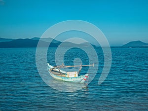 A small fishing boat is anchored near the shore