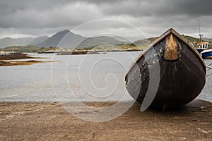 Small fishing boat ashore. Diamond hill mountain peak in clouds in the background. Harbour Derryherbert county Galway, Connemara,