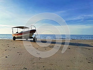 Small fishing boat on beach side with blue sky background