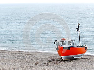 Small fishing boat beached on land with ocean in the background