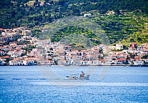 small fishing boat crossing the blue waters opposite the beautiful island of Spetses, located in Saronikos gulf near Athens