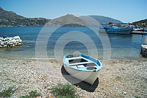 A small fishing boat, docked on a pebble beach on the Greek island of Telendos