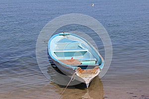 A small fishing boat without engine is moored on the beach.
