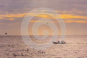Small fishing boat with fishermen on the sea near Puducherry in South India during sunrise