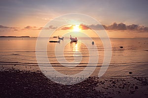 Small fishing boat of the island villagers for tourists mooring along at the beach in sunrise, South of Thailand