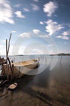 A small fishing boat on a lake, with perfectly still water and m