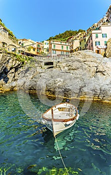 A small fishing boat moored in front of the village of Manarola, Cinque Terre, Italy