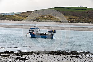 A small fishing boat moored near the shore at low tide. Seaside landscape
